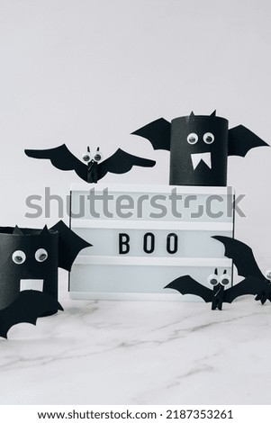 Lightbox with text BOO around paper bats. Halloween party decoration. Greeting card for autumn holiday Treat or trick