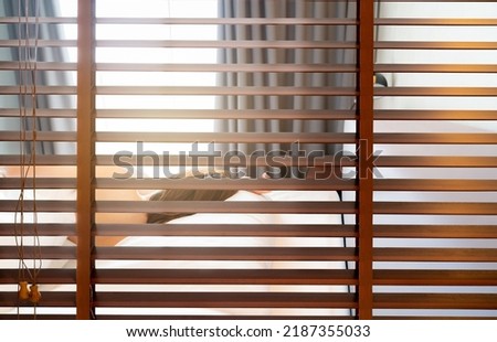 Wooden Venetian blinds. Blackout curtain between bathroom and bedroom in hotel with back view of woman sleep under white blanket on bed in the morning. Jalousie or window blinds. Horizontal blinds. Royalty-Free Stock Photo #2187355033