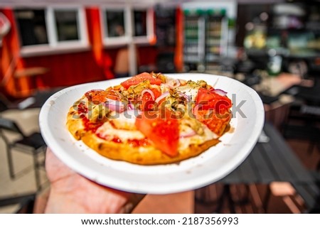 man holds plate with mini pita pizza in hands. Street food, fast food outdoor