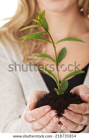 Happy woman with plant and dirt in hand