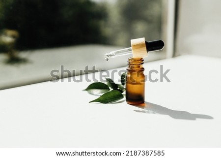 Amber bottle with serum or essential oil. Natural organic cosmetic, aromatherapy message oil. A drop of oil at the end of a pipette Royalty-Free Stock Photo #2187387585