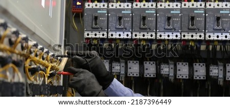 Electricity and electrical maintenance service, Engineer hand holding AC voltmeter checking electric current voltage at circuit breaker terminal and cable wiring main power distribution board. Royalty-Free Stock Photo #2187396449