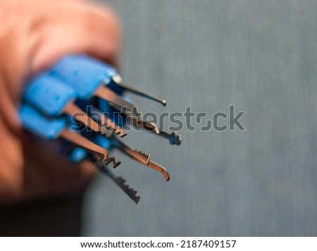 Lock picks with blue handles. Focused on Pick tips. showing part of the picking A set of locksmiths picks with sharply focused metal rakes and softly focused handles. Used for picking. Lockpicks. 