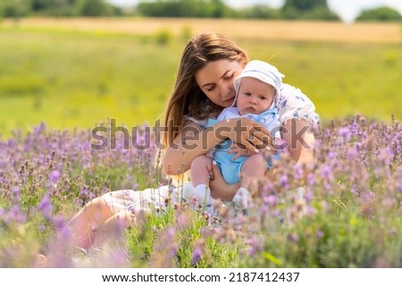 Outdoor portrait of a young baby boy with his mother relaxing in the summer sunshine in a field of lavender