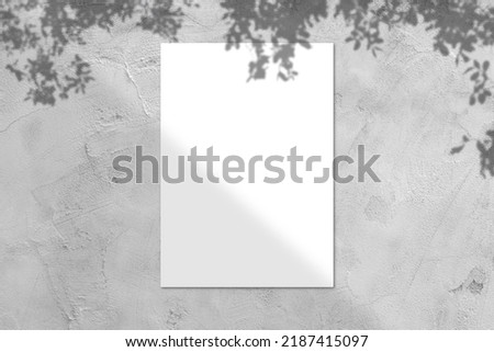Blank white square poster mockup with light shadow on gray concrete wall background., top view.
