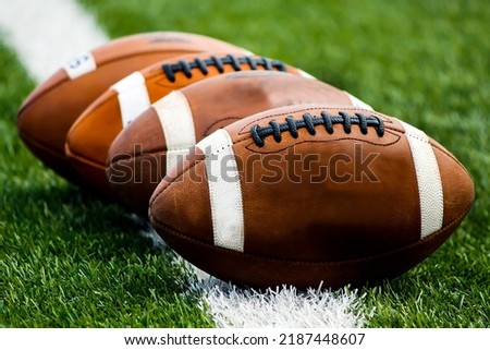 American Footballs in a row on grass
