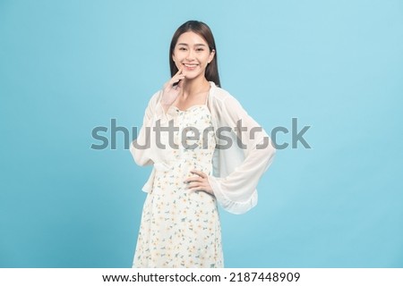 Beautiful young asian woman in white dress with flower pattern isolated on blue background