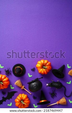 Halloween background with decorations, pumpkins, spiders, bats, witch hats and brooms, pots on purple table. Flat lay, top view, overhead