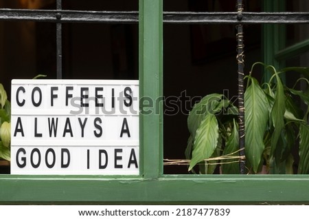 Coffee is always a good idea signboard at a window if a vintage cafe full of plants, script home decor