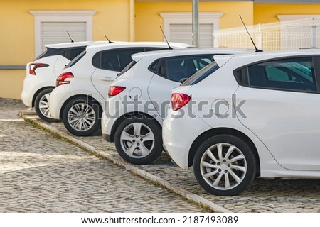Four similar white hatchback cars but from different car manufacturers parked on the cobbled street in typical European town. Budget car rental and retail concept Royalty-Free Stock Photo #2187493089