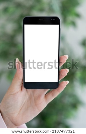 Virtual work. Digital mockup. Mobile connection. Unrecognizable woman holding smartphone with blank screen in light room interior.