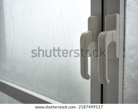 Rain drops on window with handle. Rainy weather. Closeup