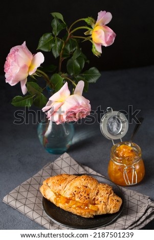 Croissant with orange jam on agray gray background