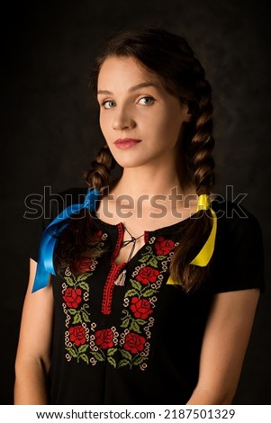A girl with braided yellow and blue ribbons, the colors of the Ukrainian flag on a dark background