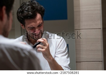 Aggressive businessman standing angry in front of mirror in the restroom after exhausting busy workday Royalty-Free Stock Photo #2187508281