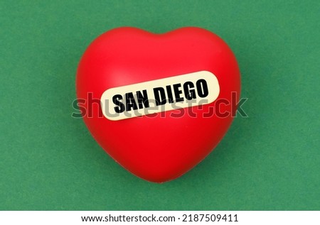 Love for the city, homeland. On a green surface lies a red heart with the inscription - San Diego