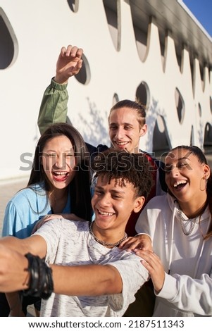 Vertical photo of a Latin guy taking a selfie with a multiracial group of people. Happy students together on campus college. 
