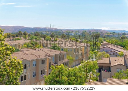 Community buildings with mediterranean design at Ladera Ranch, California. Apartment buildings with railings at the verandas and concrete tile roofs against the mountains at the background.