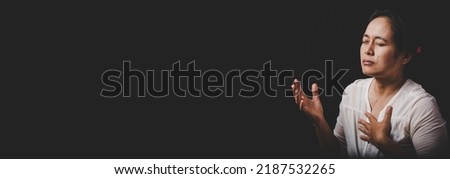 Asian christian woman person pray and worship for thank god in church with black background, The concept for faith, spirituality and religion, horizontal banner.