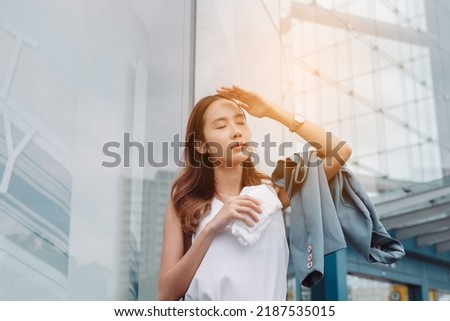 Asian businesswoman facial skin is damaged by UV attack from bright sun light in the modern city near office, Sun cream, sun block concept. Royalty-Free Stock Photo #2187535015