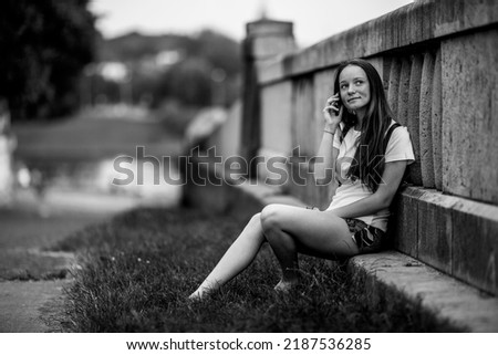 A girl talking on her cell phone outdoors. Black and white photo.