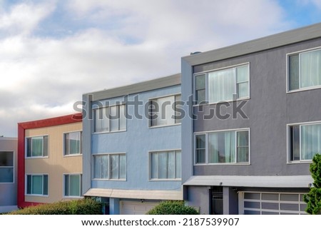 Modern house buildings with reflective picture windows in San Francisco, California. Complex houses with a view of garage doors at the bottom against the sky background.
