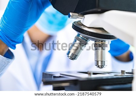 Scientist analyzing microscope slide at laboratory. Young woman technician is examining a histological sample, a biopsy in the laboratory of cancer research Royalty-Free Stock Photo #2187540579