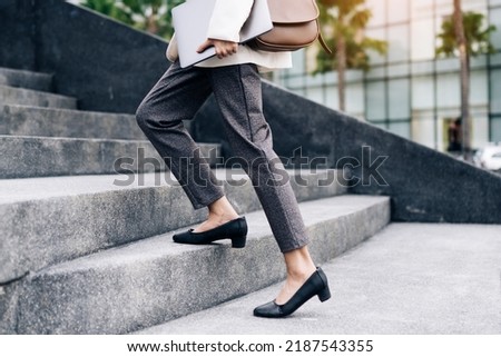 Close up legs of businesswoman hurry up walking she is late time Female business people holding laptop go to office in the modern city foot step on staircase Royalty-Free Stock Photo #2187543355