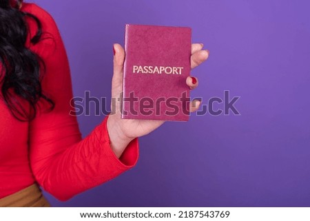 Female hand holding a passport over a violet background.