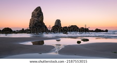 The Needles sea stacks alongside the beach at Cannon Beach Oregon during low tide at dawn Royalty-Free Stock Photo #2187553015
