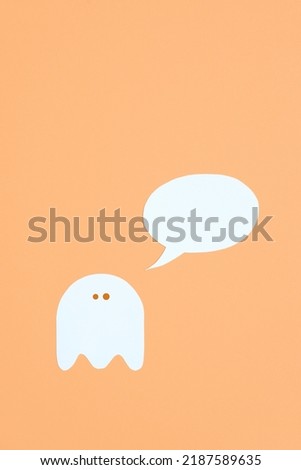 Trendy minimalist halloween design, white cute ghost with a blank speech bubble on orange pastel color background, composition with copy space.