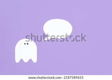 Trendy minimalist halloween design, white cute ghost with a blank speech bubble on lilac background, pastel color composition with copy space.