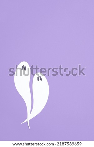 Cute minimal halloween composition, couple of white ghosts flying on lilac background, pastel color design with copy space.