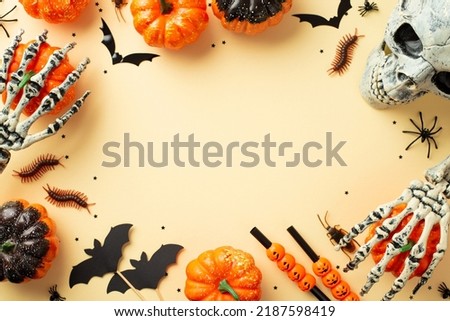 Halloween decor concept. Top view photo of pumpkins skeleton hands skull straws spiders cockroach centipedes and bats silhouettes on isolated beige background with empty space in the middle