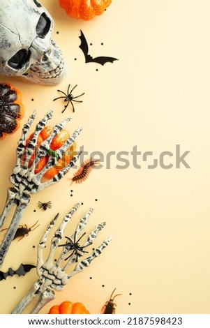 Top view vertical photo of halloween decorations skull skeleton hands pumpkins bat silhouettes spiders cockroaches centipede and black confetti on isolated beige background
