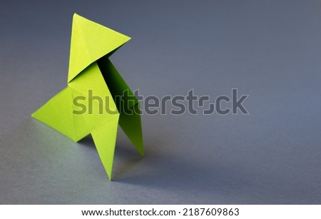 Green paper hen origami isolated on a blank grey background. Cocotte en papier