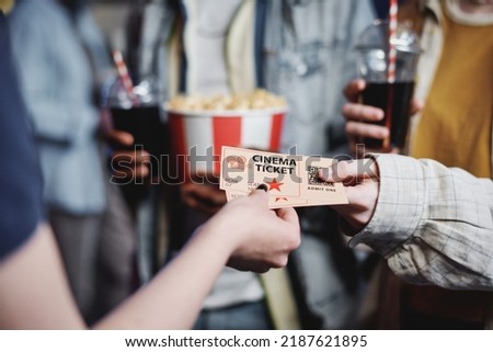 Unrecognizable people giving tickets for movie to cinema worker to enter hall, selective focus shot Royalty-Free Stock Photo #2187621895