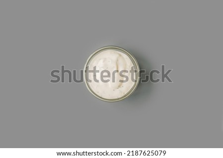 Gravy boat with mayonnaise with greenery on a gray background, top view. Isolated.