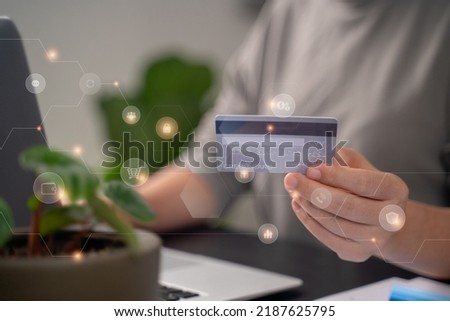 Close up shot of females  hands holding credit card typing message on laptop for shopping online with technology icons at home office.