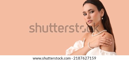 Beautiful young woman wearing stylish pearl jewelry on beige background with space for text Royalty-Free Stock Photo #2187627159
