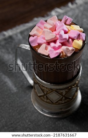 Cocktail with marshmallows in a glass that stands on a table surrounded by a room