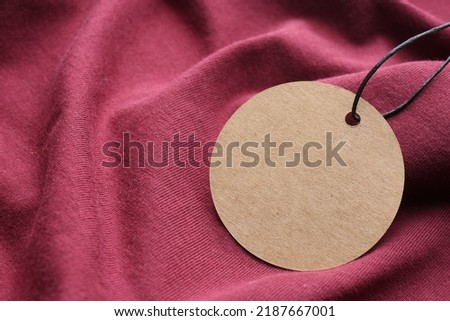 Circle shaped tag with space for text on dark red fabric, closeup
