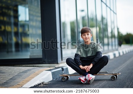 Teenager boy in a sports suit with longboard.
