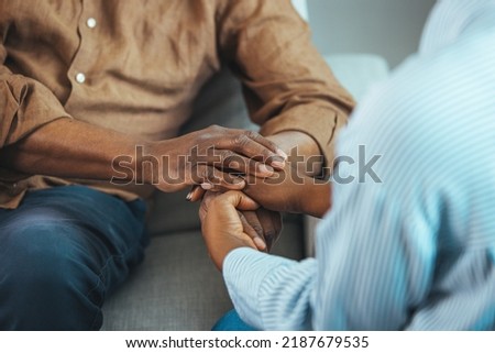 Close up black woman and man sitting on couch two people holding hands. Symbol sign sincere feelings, compassion, loved one, say sorry. Reliable person, trusted friend, true friendship concept Royalty-Free Stock Photo #2187679535