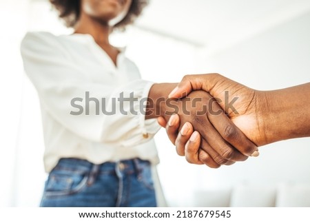 Happy multiethnic businesspeople shake hands close deal make agreement at meeting in office. Smiling African American handshake excited female client, get acquainted at briefing. Royalty-Free Stock Photo #2187679545