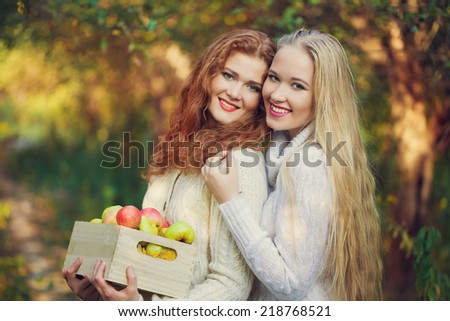 Two sisters in Fall yellow apple orchard. Autumn outside in colorful fall forest 