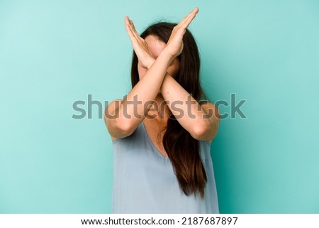 Young caucasian woman isolated on blue background keeping two arms crossed, denial concept.