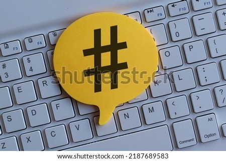 Top view image of computer keyboard and speech bubble with hashtag icon.