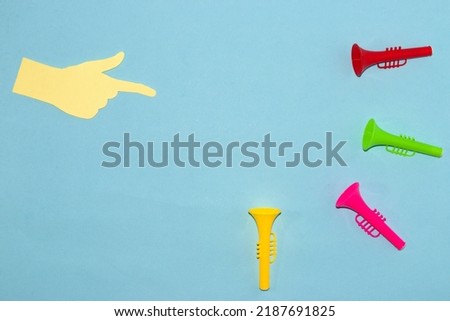 finger pointing to empty space and colorful trumpets pointing to empty space, abstract background space for text and product