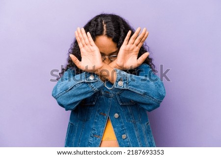 Young hispanic woman isolated on purple background keeping two arms crossed, denial concept.